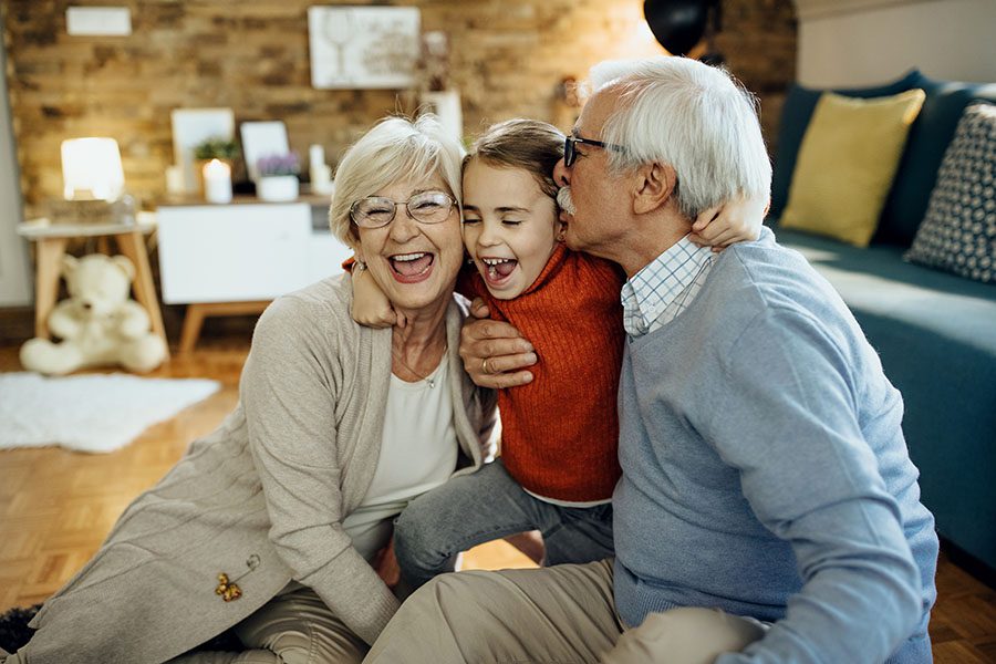 Client Center - Portrait of Cheerful Grandparents Sitting in the Living Room Having Fun Playing with Their Granddaughter